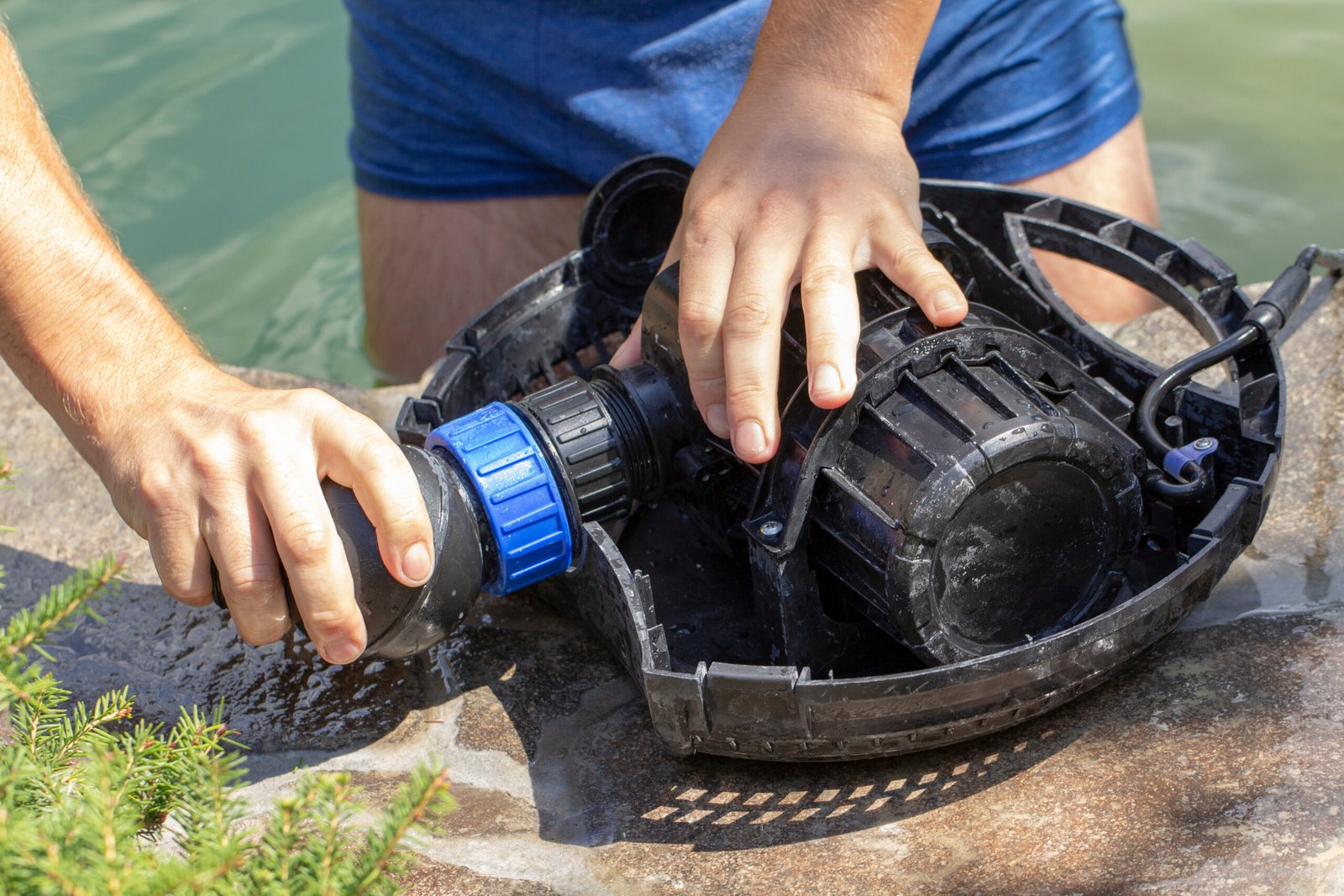 Person performing maintenance on a water pump by removing a component from the device.