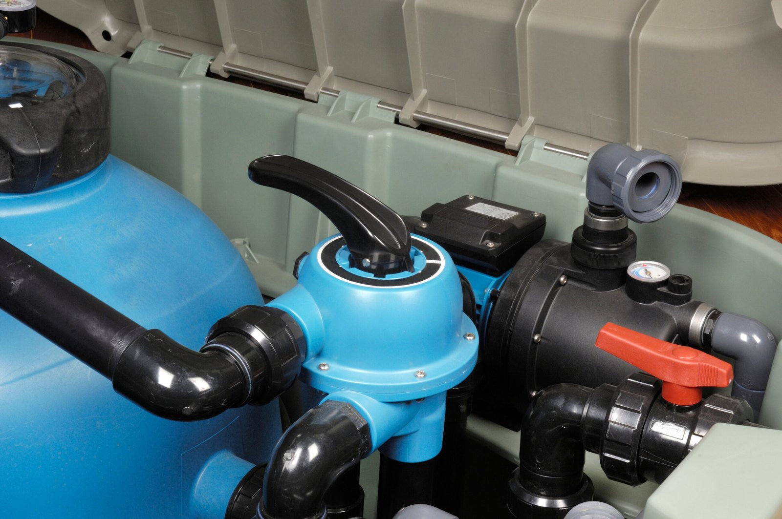 Close-up of a blue water pump with various connected pipes and valves in a water filtration system.