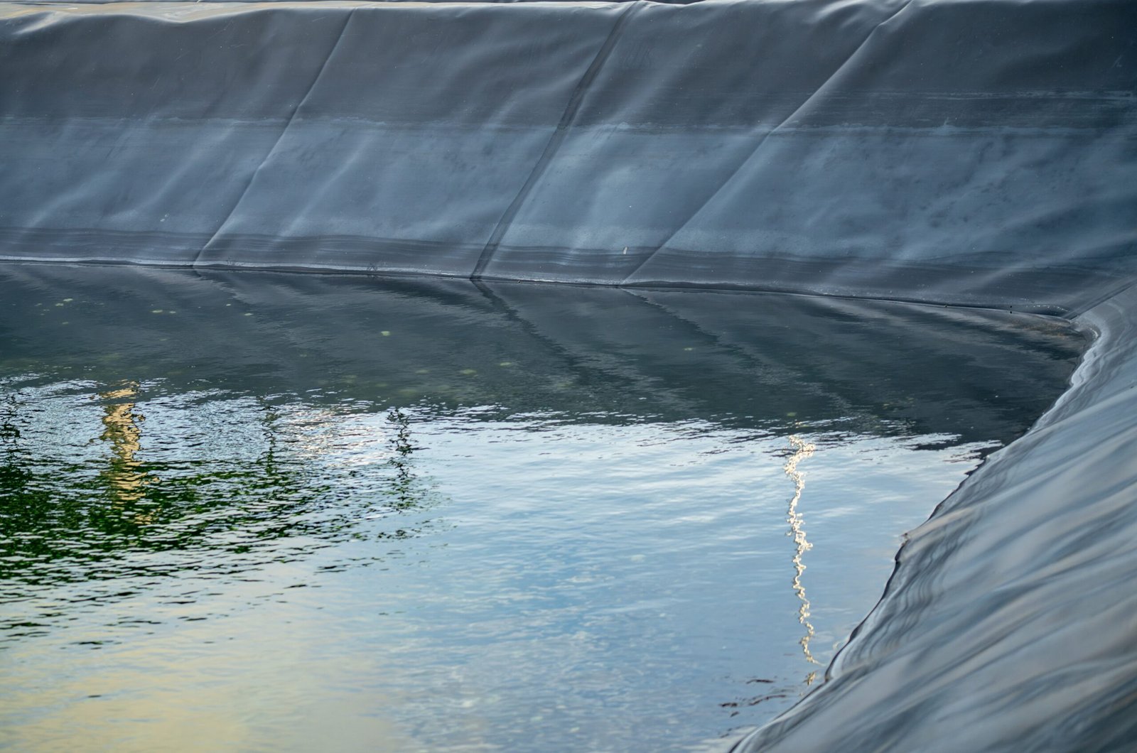 Water garden liner with a smooth, reflective surface and a curved edge, showing clear water within.